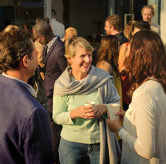 woman smiling with a cup in her hand at party with other people smiling