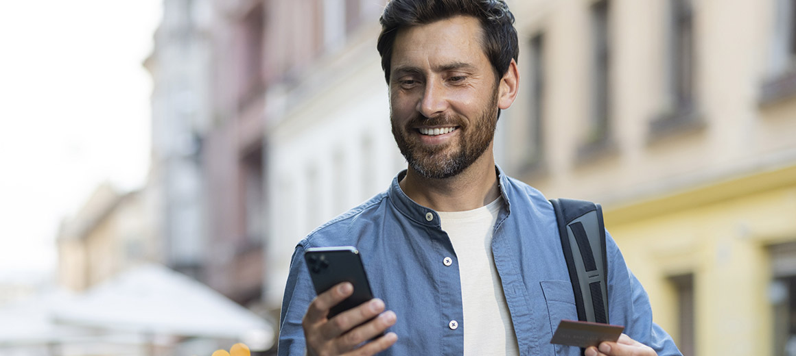 man who looks like he is on travel looking at his phone also holding a card