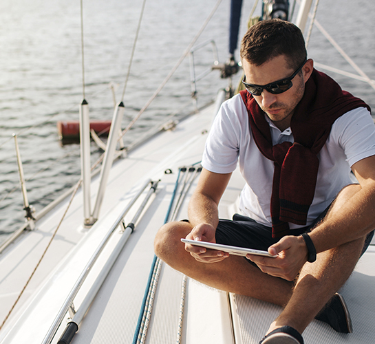 man looking at tablet on a sailboat