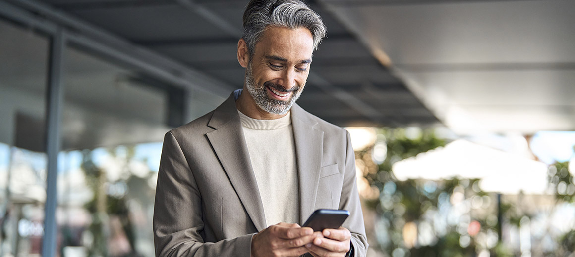 businessman standing outside smiling at his phone